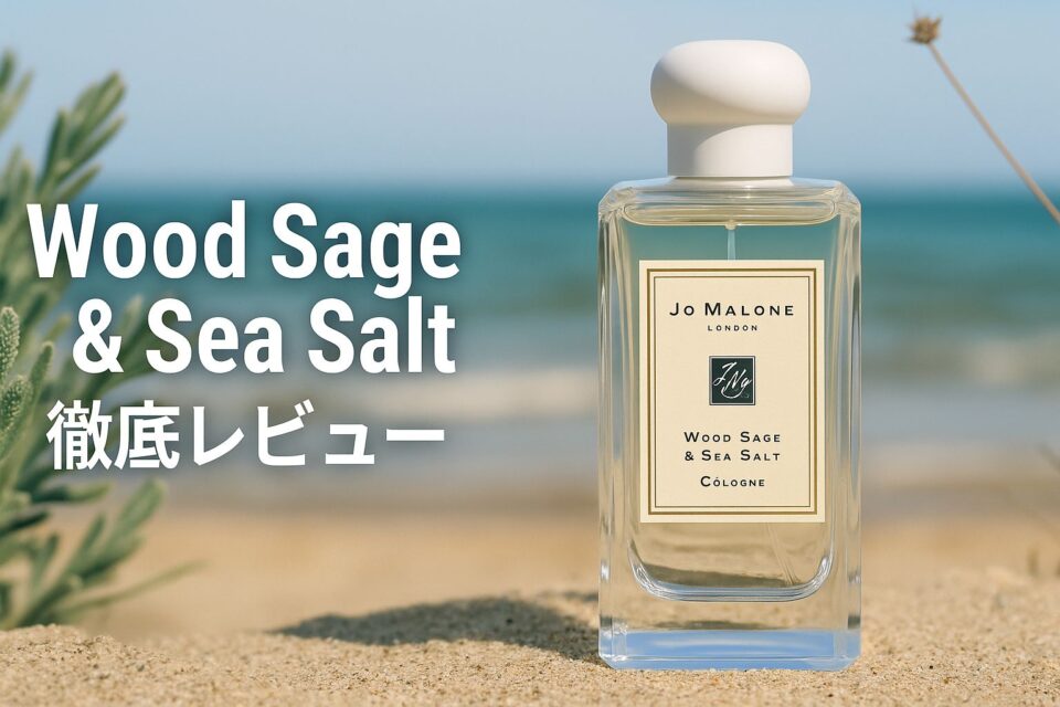 「Jo Malone『Wood Sage & Sea Salt』のコロンボトルが砂浜に置かれ、海と緑を背景に撮影された写真広告風アイキャッチ。自然な海風とセージの雰囲気を感じさせるラグジュアリーなイメージ。」
