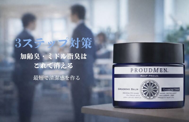 プラウドメン グルーミングバームがオフィスのデスク上に置かれ、背景にはスーツ姿の人物がぼかされている清潔感のあるイメージ画像